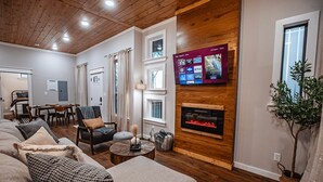 Una sala de estar acogedora con chimenea, un televisor montado en la pared y un comedor con mesa y sillas.