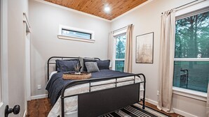 Un dormitorio con cama, ventana, puerta y lámpara en el techo.