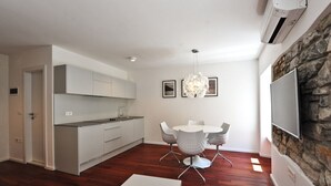 A modern kitchen with white cabinets and a dining area with a white table and chairs. - Downtown Piran Apartment with City View - Studio Apartment (Piran)