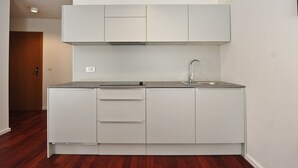 A compact kitchen with white cabinets, a stainless steel sink, and a built-in range hood. - Downtown Piran Apartment with City View - Studio Apartment (Piran)