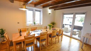 Un coin repas avec une table et des chaises en bois, une plante en pot, des bougies et une bouteille de vin.