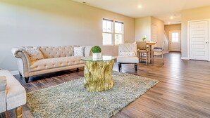 Een ruime woonkamer met een beige bank, een glazen salontafel en een houten bijzettafeltje.