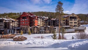 A multi-story hotel with a ski lift visible in the background, surrounded by snow-covered terrain and trees.