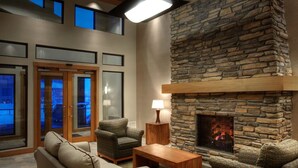 A cozy living area with a stone fireplace, comfortable seating, and a view through the glass doors.