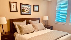 A bedroom with a bed, two nightstands, a ceiling fan, and three framed pictures on the wall.