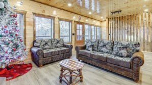 Ein rustikales Blockhaus-Interieur mit zwei Sofas, einem Couchtisch und einem Weihnachtsbaum.