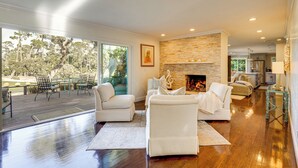 A modern living room with a fireplace, white furniture, and a view of the outdoors. - Golfer's Oasis: Luxe Pebble Beach Home on 5th Hole (Pebble Beach)