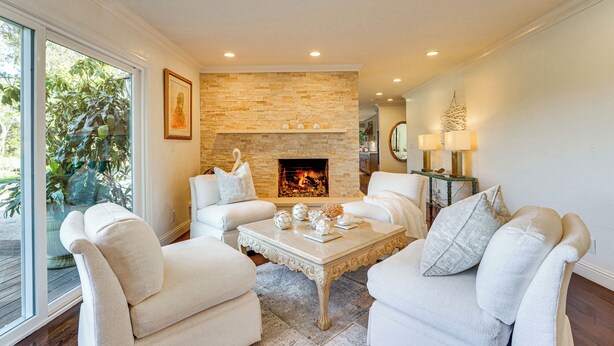 A modern living room with a stone fireplace, white furniture, and a large window. - Golfer's Oasis: Luxe Pebble Beach Home on 5th Hole (Pebble Beach)