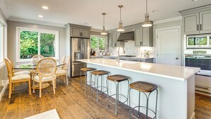 A modern kitchen with a large island, bar stools, and stainless steel appliances. - Golfer's Oasis: Luxe Pebble Beach Home on 5th Hole (Pebble Beach)