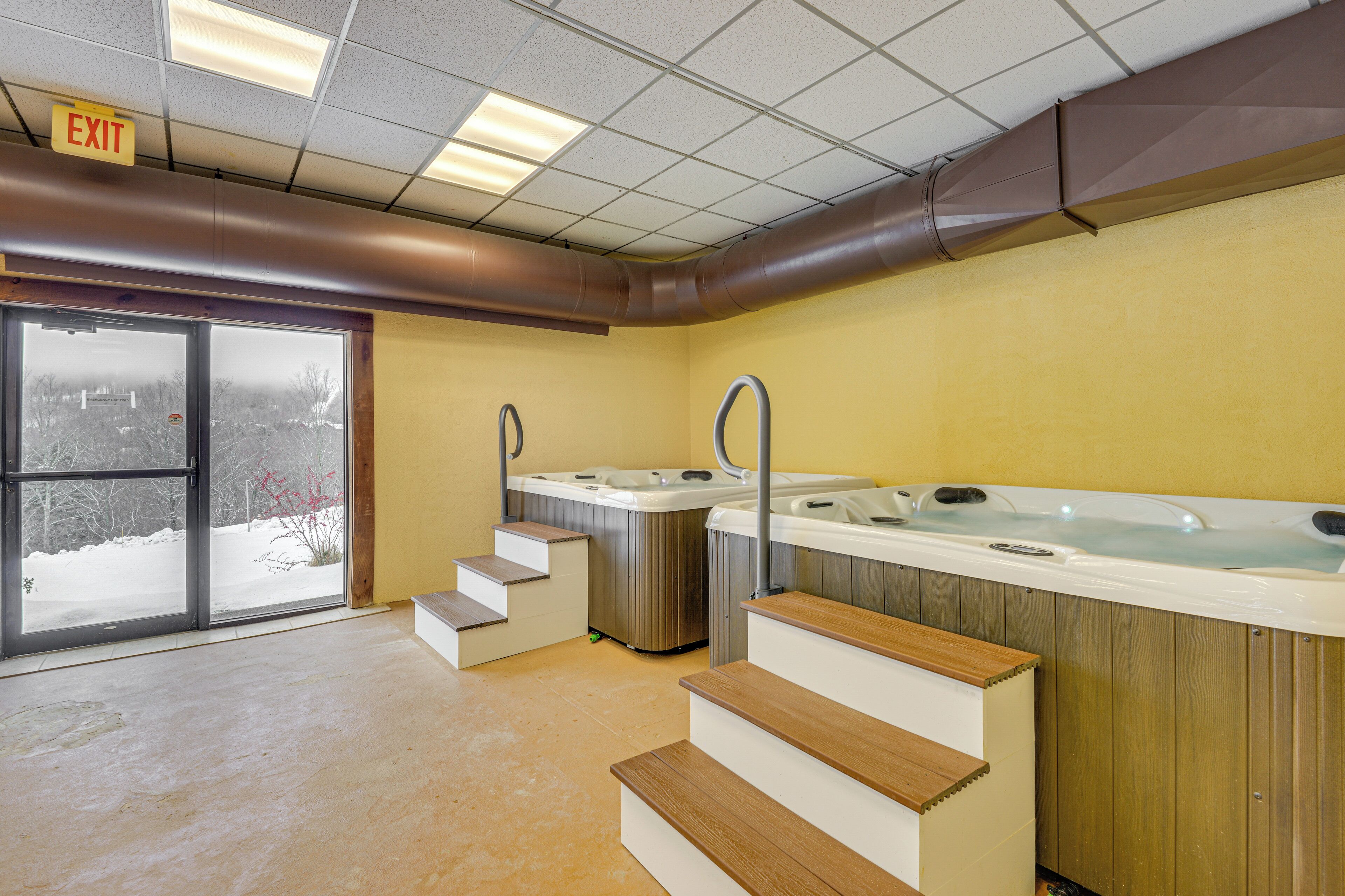 A spa area with two hot tubs, wooden steps, and an exit sign.