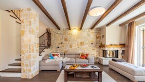 A cozy living room with a stone wall, a fireplace, and a staircase. - Villa Forte with Heated Private Pool close to the Beach (Porat (Krk))