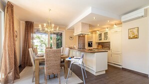 A modern kitchen with a central island, white cabinetry, and a chandelier. - Villa Forte with Heated Private Pool close to the Beach (Porat (Krk))