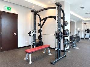 Ett gym med en bänk, styrketräningsutrustning och ett löpband.