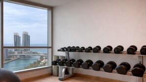 A gym with a view of a cityscape through large windows, a rack of dumbbells, and a yoga ball. - Cozy Studio Dubai Marina by beach & Metro (Dubai Marina)