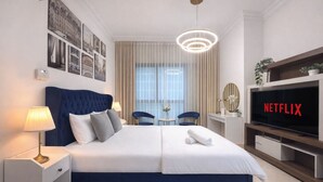 A modern hotel room with a large bed, a TV, and a dining area with chairs. - Cozy Studio Dubai Marina by beach & Metro (Dubai Marina)