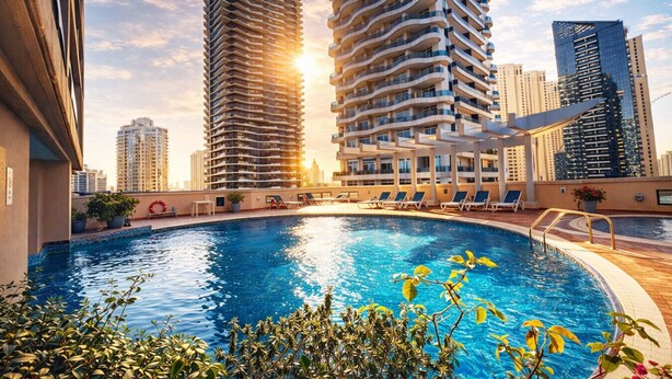 A rooftop pool with lounge chairs, surrounded by high-rise buildings, under a clear sky. - Cozy Studio Dubai Marina by beach & Metro (Dubai Marina)