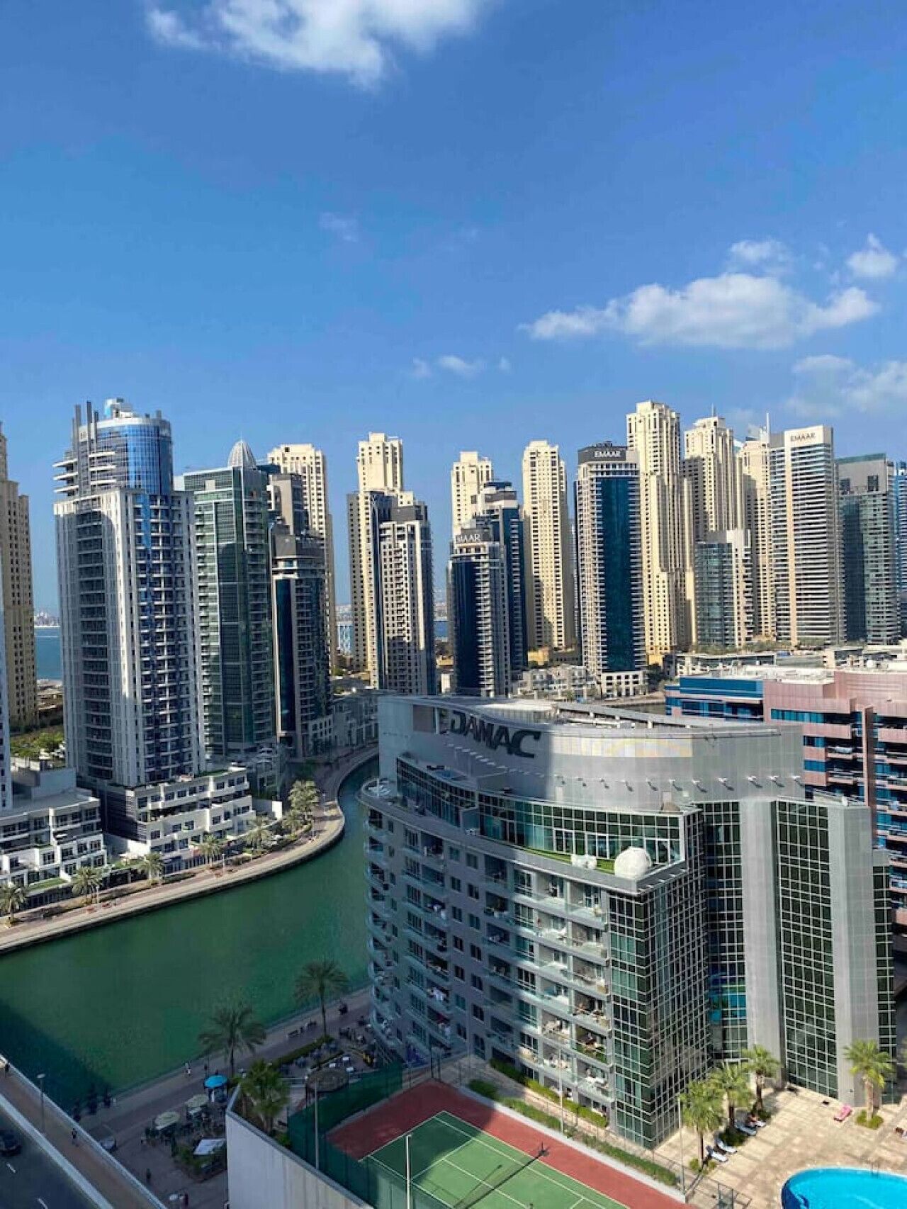 A high-rise building with a marina in the foreground, surrounded by other tall buildings.