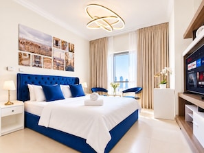 A modern hotel room with a large bed, a television, and a cityscape view. - Cozy Studio Dubai Marina by beach & Metro (Dubai Marina)