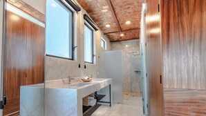 Ein modernes Badezimmer mit Marmorwaschtisch, Holzschränken und einer Ziegeldecke.