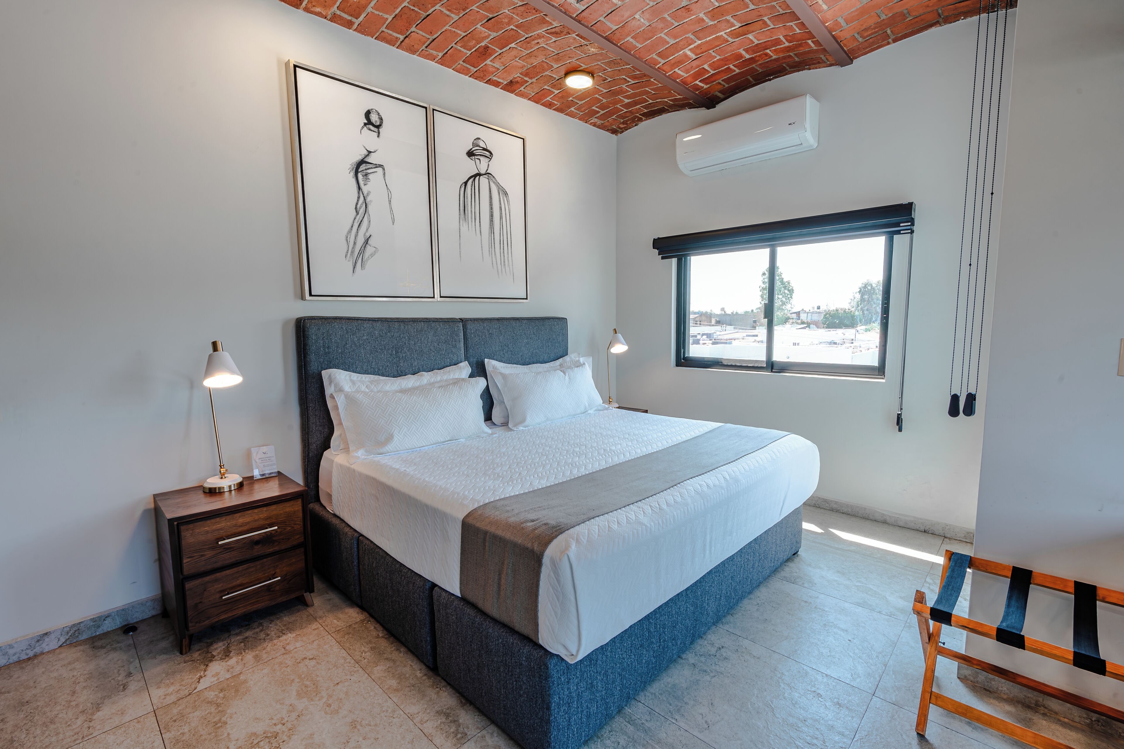 Un dormitorio con cama, mesita de noche y ventana.
