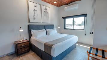 Un dormitorio con cama, mesita de noche y ventana.