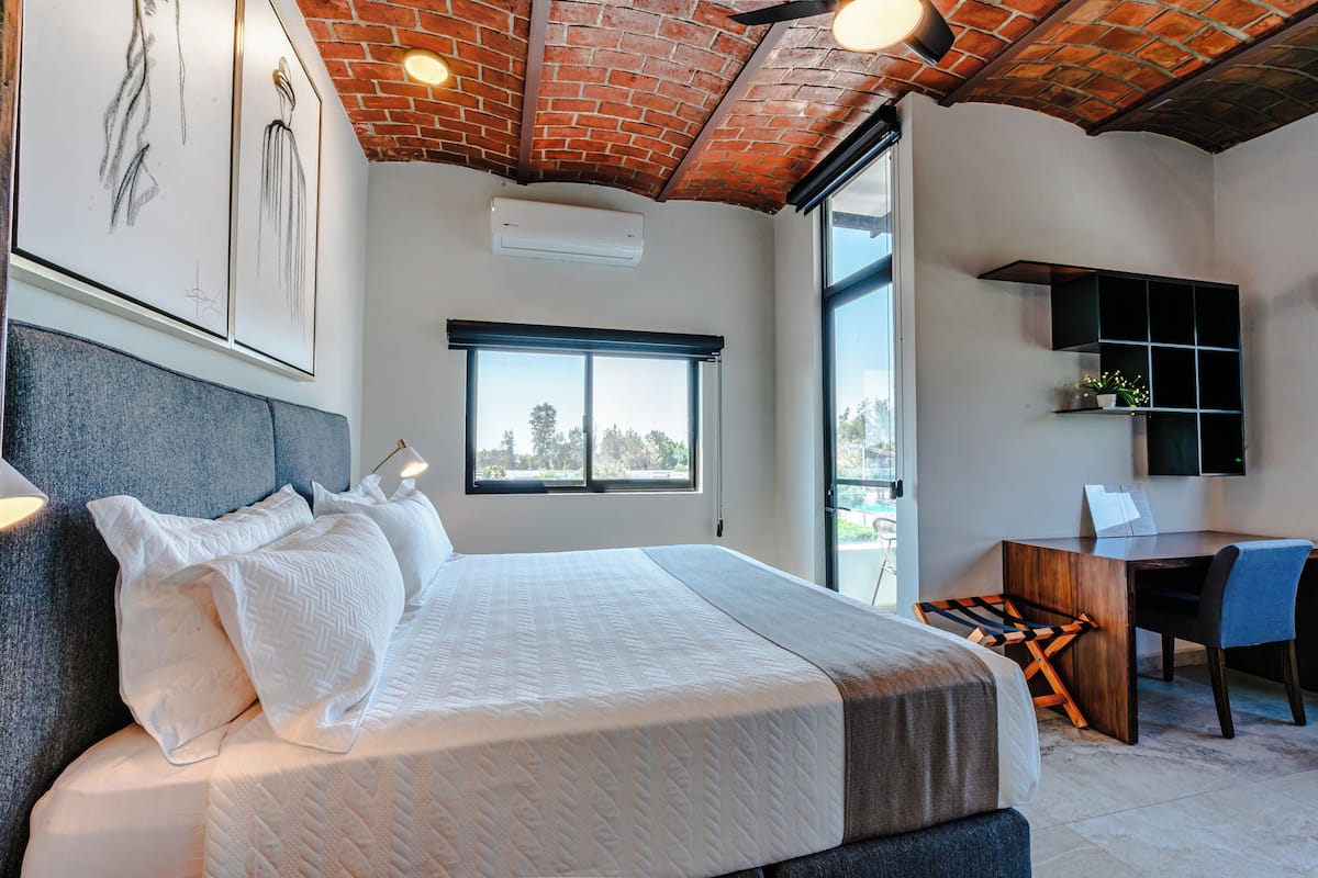 Quarto moderno com uma cama grande, uma escrivaninha e vista para o exterior.