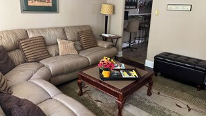 A living room with a leather sofa, a wooden coffee table with magazines, and a framed picture on the wall.