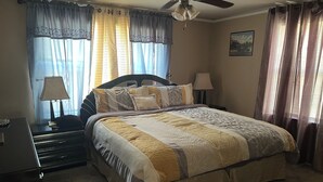 A neatly made bed with a patterned bedspread, a bedside lamp, and a nightstand with a lamp.