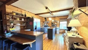 Una cocina acogedora con pisos de madera, una isla central, taburetes de bar y una mesa de comedor.