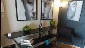Una sala de estar moderna con una consola negra, un sillón azul y dos cuadros abstractos en la pared.