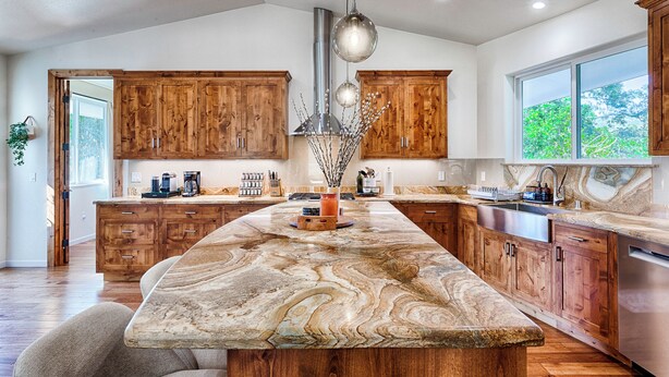 A spacious kitchen with wooden cabinets, a marble island, and a large window providing natural light. - Modern Farmhouse with Pool & Vineyard (Santa Rosa)