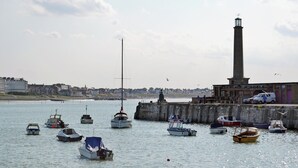 A harbor with various boats, a lighthouse, and a coastal town in the background. - Beach Oasis Cottage - UK48530 (Margate)