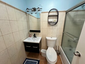 Ein Badezimmer mit weißem Waschbecken, schwarzem Schrank und Toilette.