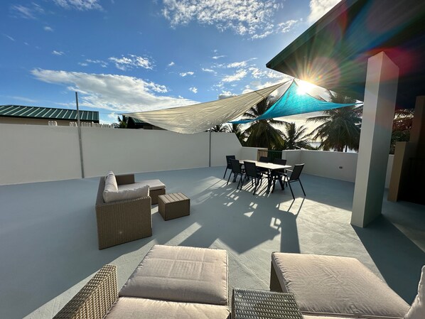 Eine Dachterrasse mit Gartenmöbeln, einem Tisch und Sonnenschirm.