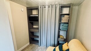 Ein Schlafzimmer mit einem Bett, einem Schrank mit Regalen und einem Fenster mit Vorhängen.
