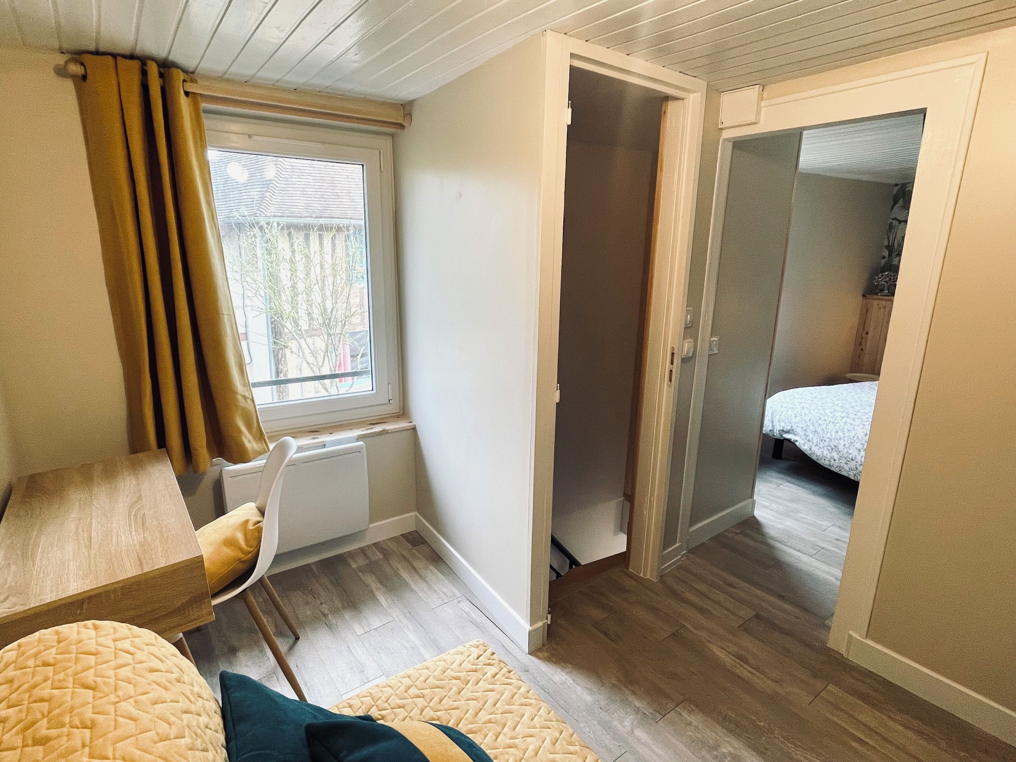 A compact room with a wooden floor, a bed, a chair, and a radiator.