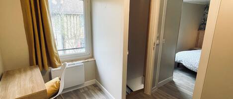 A compact room with a wooden floor, a bed, a chair, and a radiator.
