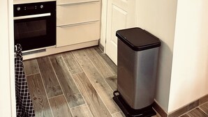 Eine kompakte Küche mit integriertem Backofen, einer Mikrowelle und einer kleinen Mülltonne.