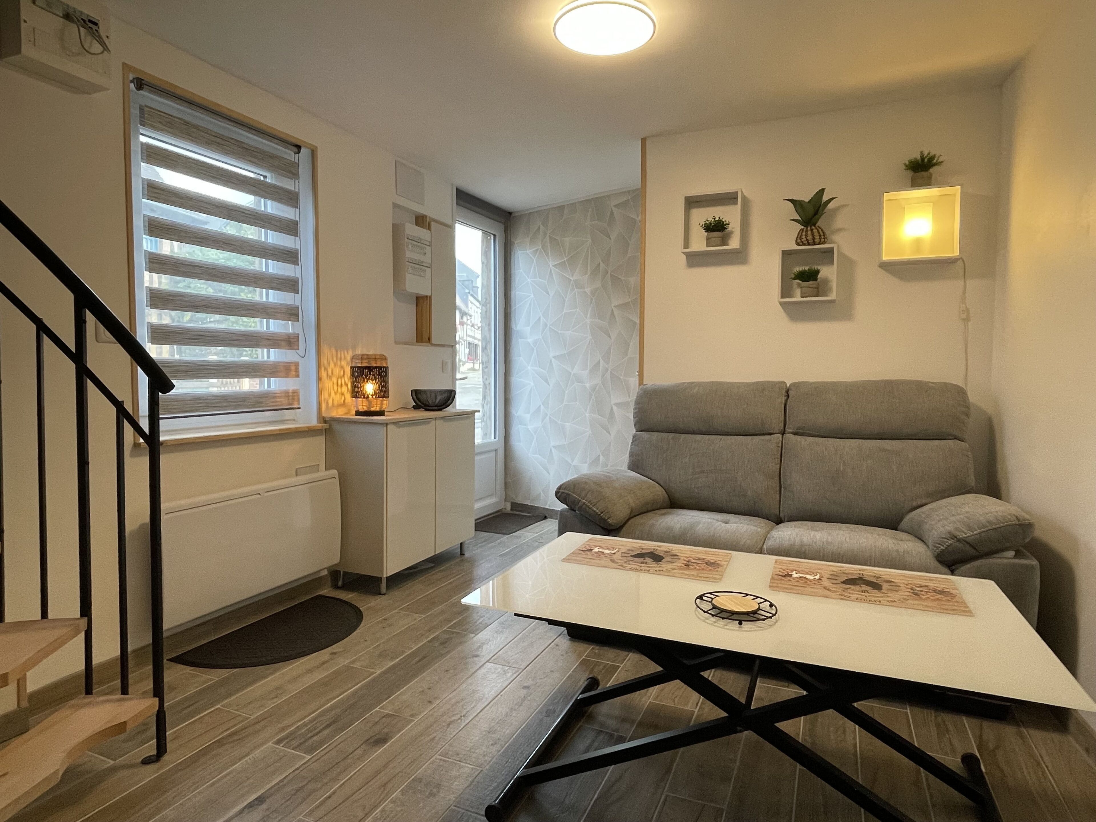 A modern living room with a grey sofa, a white coffee table, and a staircase.