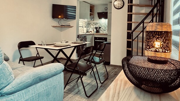 Ein modernes Wohnzimmer mit Essbereich, einer Treppe und einer Küche im Hintergrund.