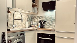 Eine kleine Küche mit Waschmaschine, Backofen und Mikrowelle.