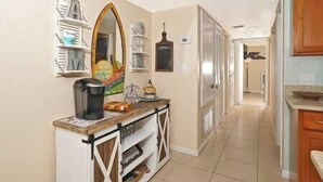 A kitchen with a coffee maker, a microwave, and a shelf with various items.