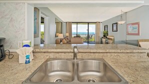 A hotel kitchen with a double sink, a coffee maker, and a bottle of dish soap.