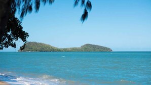 Ein Strand mit klarem, blauem Wasser, einem sandigen Ufer und einer entfernten Insel.