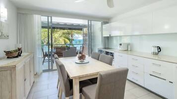 A modern kitchen with a dining area, large windows, and a view of the outdoors.