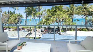 Ein Balkon mit weißer Möbel, Blick auf den Strand und Palmen.