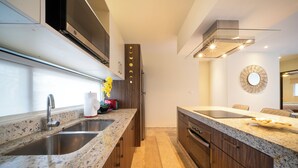 A modern kitchen with granite countertops, stainless steel sinks, and wooden cabinets. - Modern PH with 2 Br & Pool at Arena 509 (Playa del Carmen)