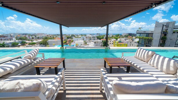 A rooftop pool area with lounge chairs and a view of the cityscape. - Modern PH with 2 Br & Pool at Arena 509 (Playa del Carmen)