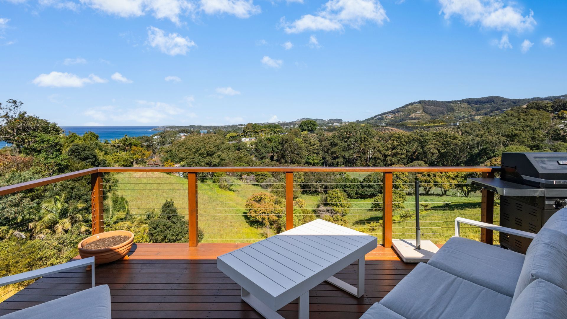 A deck with a view of a coastal landscape, including hills and a body of water.