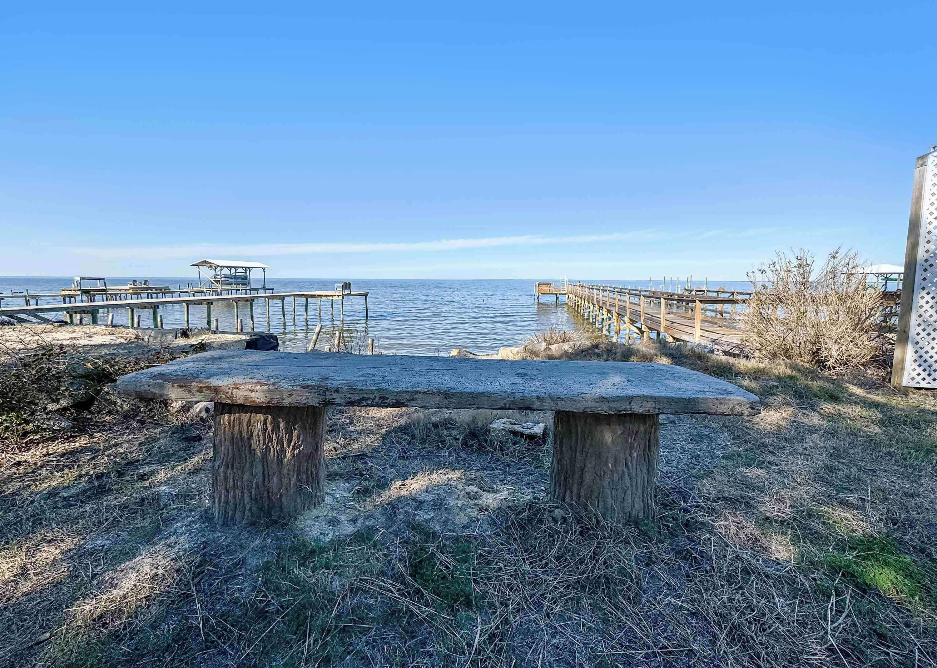 A bench overlooking a calm body of water with wooden docks extending into the water.